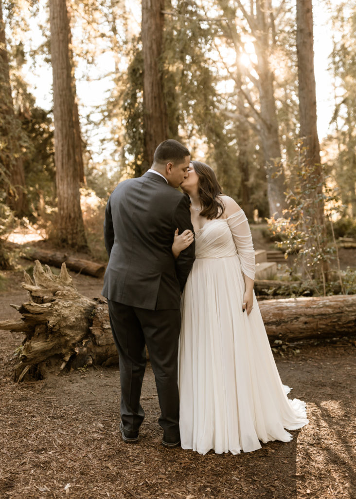 Bride and groom hugging and kisses in a redwood forrest